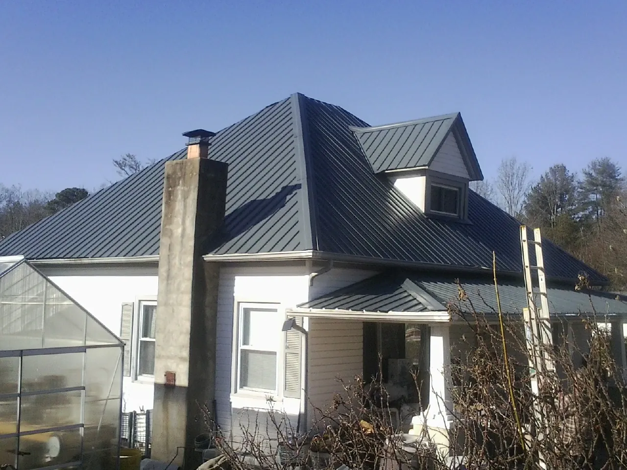 Dark blue standing seam metal roof on a white farmhouse with dormer — Slate & Tile Roof Repair by Roofing Brothers in Valyermo