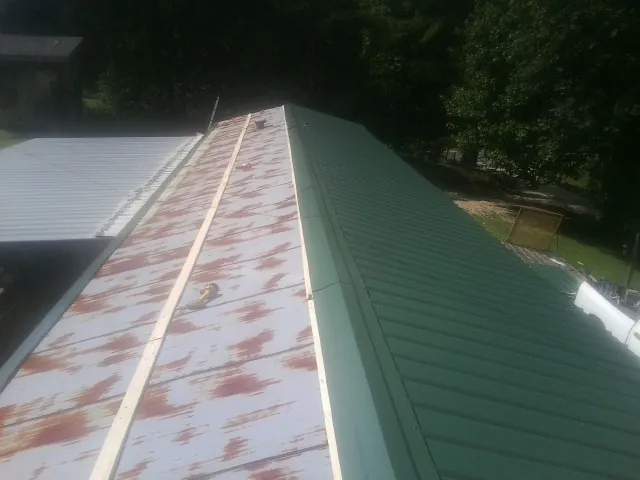 Old rusted panels beside newly installed green metal roofing — Wind Damage Roof Repair by Roofing Brothers in Valyermo