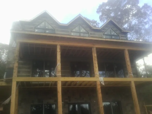 Dormers and porch framing on a large log home under construction — Roof Coating work by our crew in Valyermo